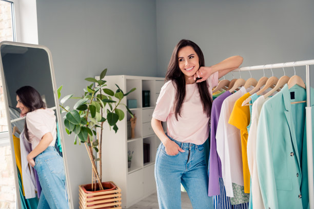 积极的女士站在衣架附近的照片，看朋友在房子的陈列室里为聚会活动挑选衣服图片下载