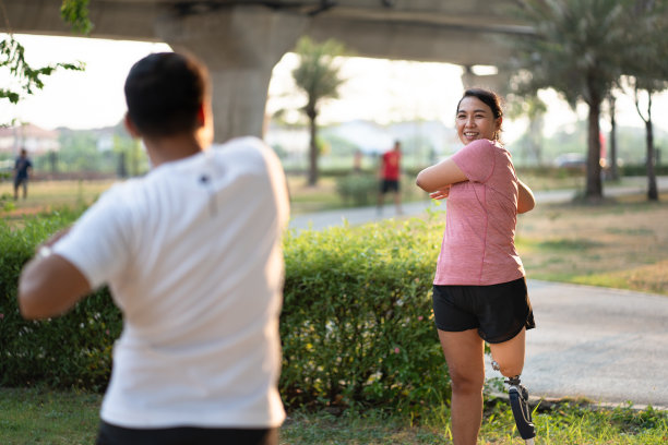 运动亚洲女人用义肢和朋友在公园城市伸展图片下载