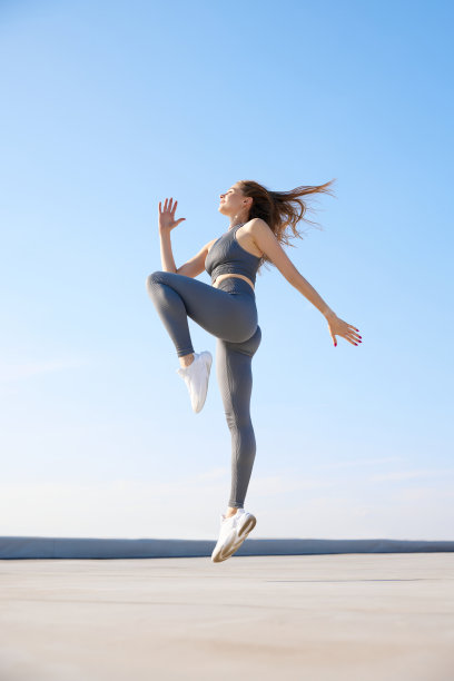 在温暖的夏日里，穿着舒适运动服的年轻女子在户外训练。伸展运动图片下载