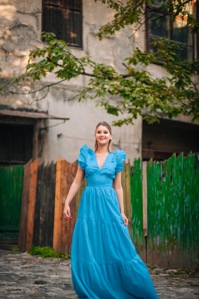 美丽的年轻女子穿着蓝色长裙漫步探索古城图片下载