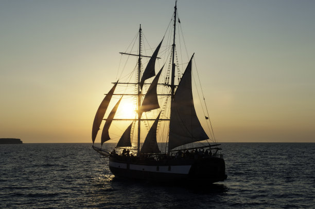 希腊圣托里尼岛，日落时海上的帆船图片下载