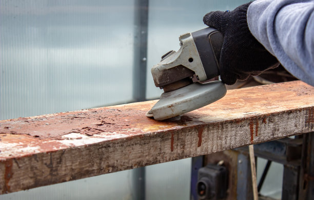 一个男人正在磨一块木板。清除木板上的旧漆。木工工作。图片下载