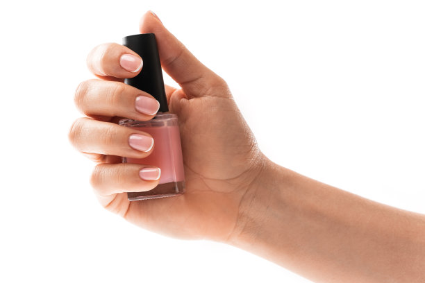 女性手与美丽的法国美甲持有瓶粉红色指甲油对白色背景图片下载