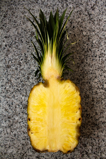 把菠萝切成两半放在石桌上图片下载