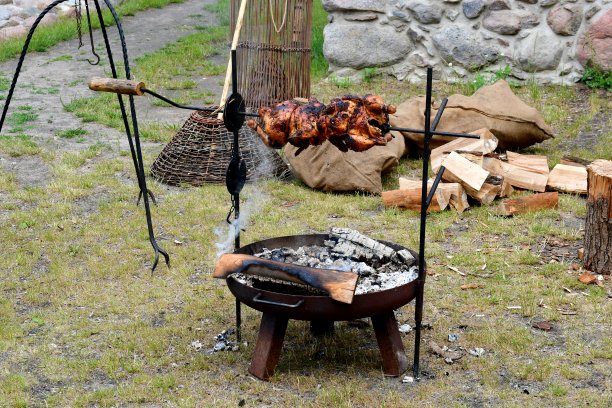 在中世纪的节日或集市上，在田野或草地旁的木制炉子或带有金属框架的烤箱上，近距离拍摄一只美味的鸡肉，经过蒸煮和烘烤图片下载
