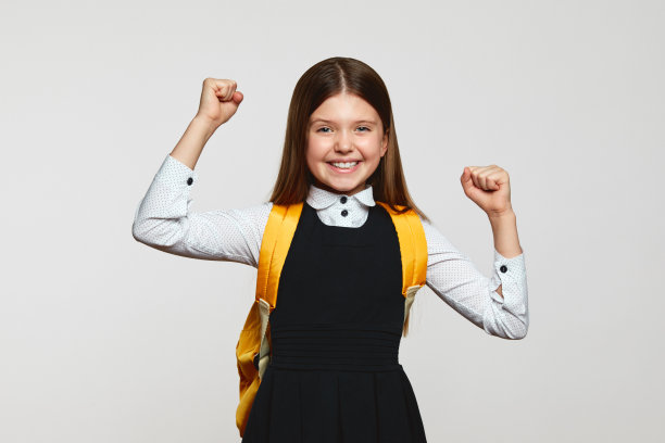 穿着校服的小女孩高举双手庆祝成功和胜利图片下载