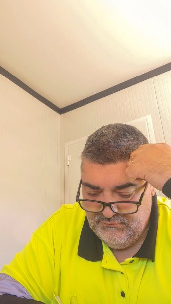 在警卫室工作的男子戴着眼镜，穿着黄色反光背心沉思图片下载