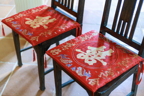 两张传统中式婚礼椅的坐垫上装饰着“双喜”的标志，这通常与婚礼有关。图片下载