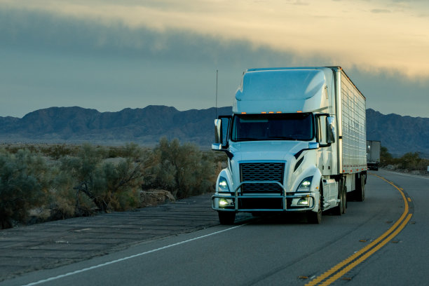 一辆白色半挂车行驶在加利福尼亚西南部的双车道高速公路上，天空中有美丽的云彩图片下载