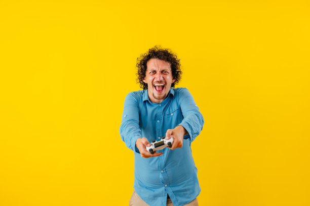 快乐的年轻人在黄墙前玩电子游戏图片下载