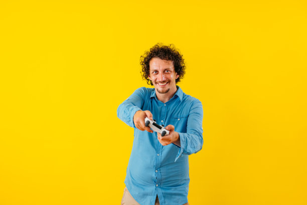 快乐的年轻人在黄墙前玩电子游戏图片下载