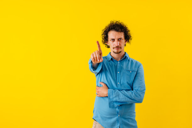 不满的年轻人在黄墙前挥动手指图片下载