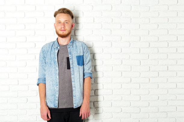 靠在白砖墙上的年轻性感男人图片下载