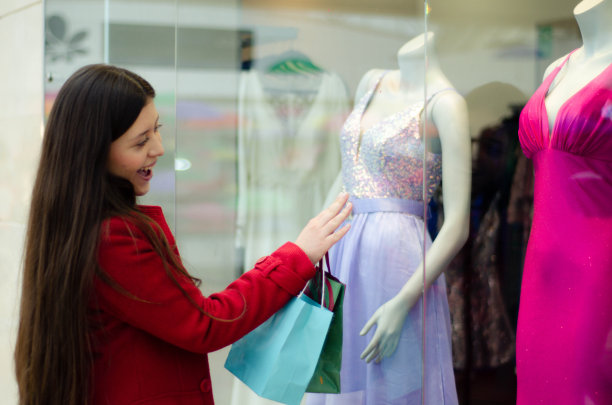 看橱窗的女人。一名年轻女子在购物时走过商店的陈列品。一位女士在购物中心挑选衣服的画像图片下载
