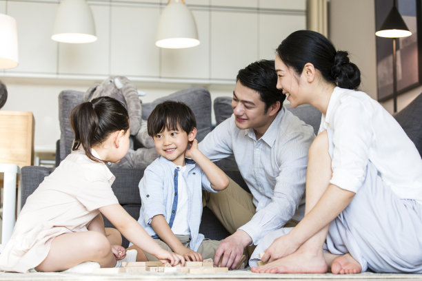 一对父母陪着他们的两个儿子和女儿在客厅的地毯上玩积木——照片图片下载