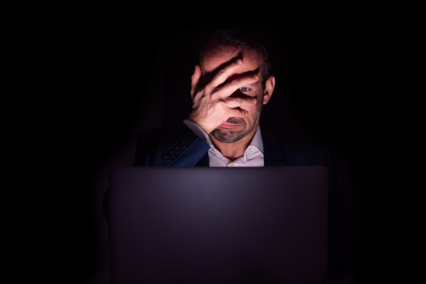沮丧的商人看起来疲惫不堪，用手捂着脸坐在笔记本电脑前图片下载
