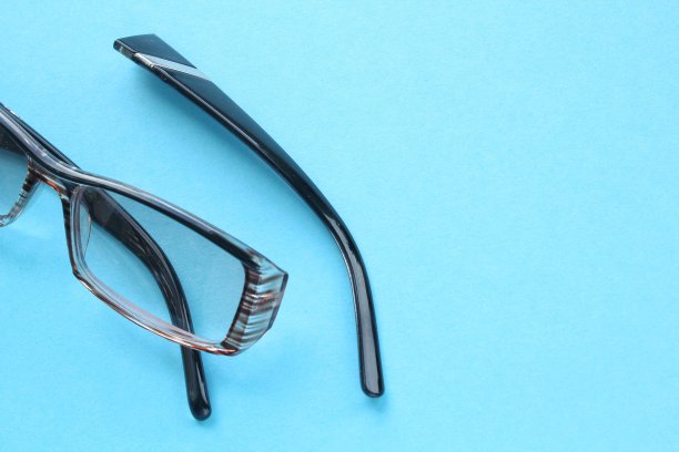 蓝色背景上的旧破眼镜和破损的眼镜腿。视力不佳。重用和修复概念。健康理念图片下载
