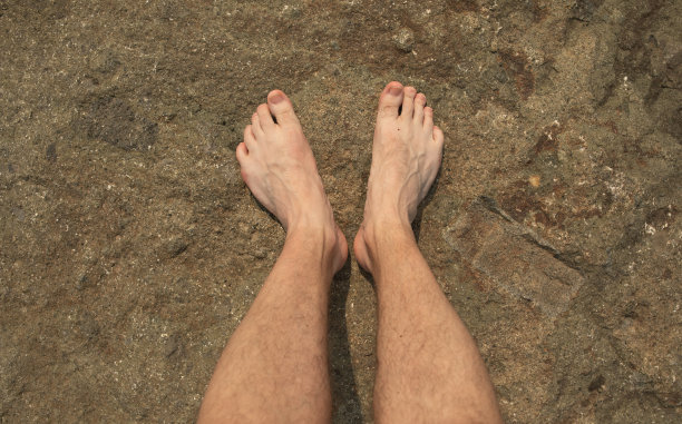 光着脚站在水边的岩石上。那人双脚站在石头上。图片下载