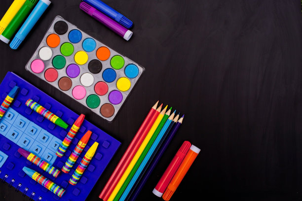 黑色背景和许多彩色铅笔。学校用品摆放在黑色的背景上——俯视图。回到学校。图片下载