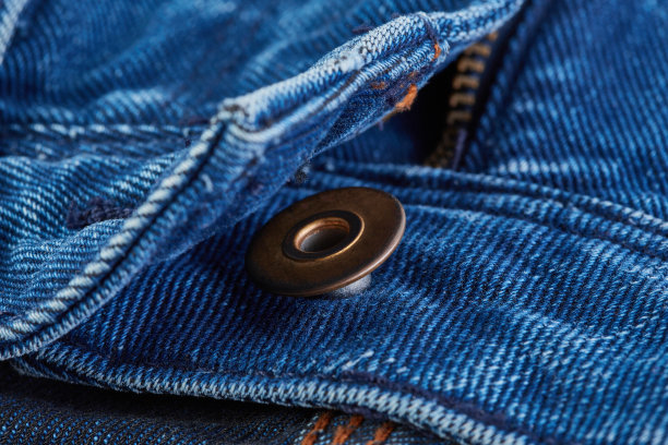 牛仔牛仔裤的纹理背景与撕裂。彩色棉织物的质地。缝制纹理牛仔裤背景。时尚牛仔裤纽扣。牛仔裤上的口袋和铆钉。纤维和织物结构。图片下载