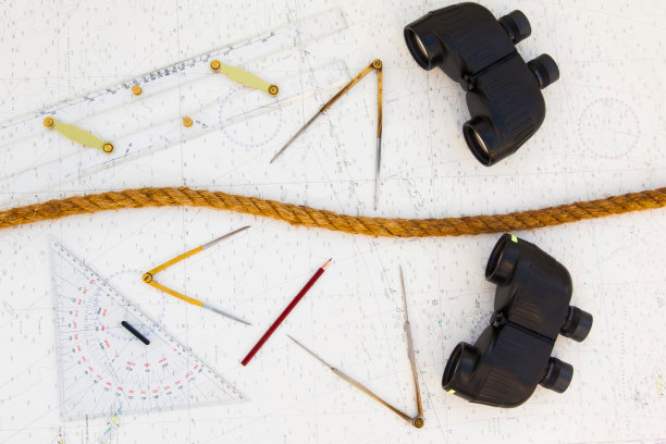 导航工具在导航地图上。绘图仪、分隔器、尺子、铅笔和双筒望远镜以及马尼拉绳。图片下载