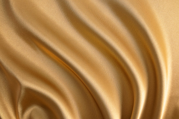 抽象的金色缎面背景豪华的织物。柔软柔软的波浪织物。织物的金色质感。喜庆，新年的背景。图片下载