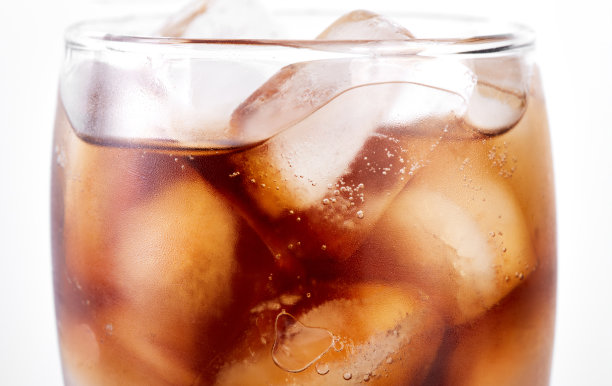 可乐装在玻璃杯里，白色背景上有吸管和冰块。苏打水与气泡隔离在白色上。清爽的无酒精饮料图片下载