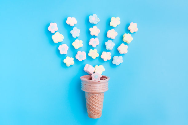 五彩棉花糖从冰淇淋筒在蓝色背景，花形棉花糖图片下载