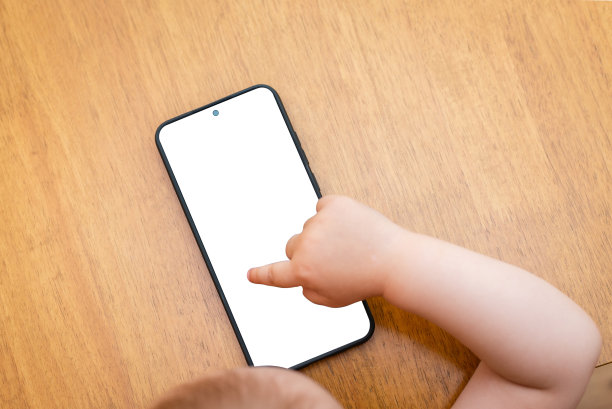 对科技上瘾。白色手机屏幕模型。小男孩在用手机。婴儿，婴儿上网。桌上的智能手机屏幕是空的。在室内拍摄。图片下载