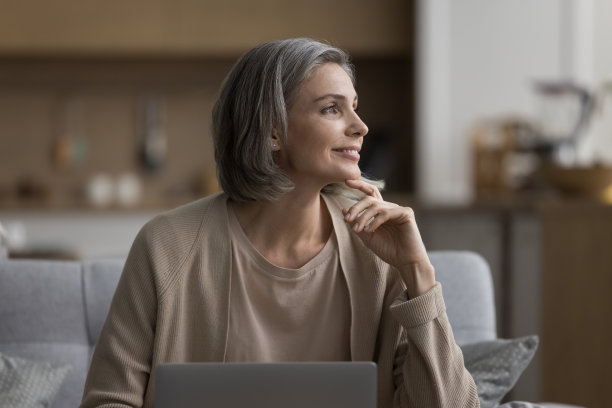 快乐体贴的白发女人膝上抱着笔记本电脑图片下载