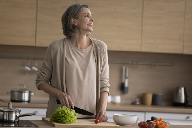 快乐的中年妇女在家庭厨房享受烹饪活动图片下载