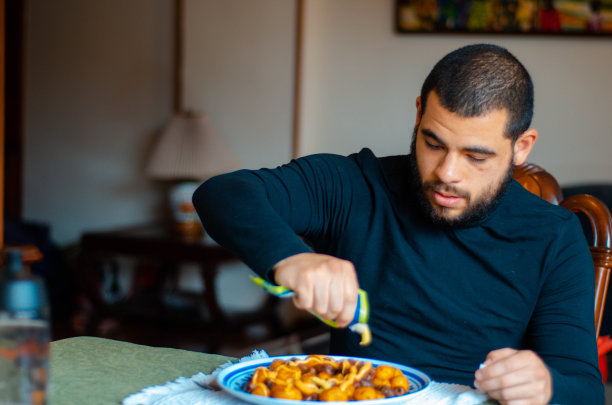 一个人在餐桌上给他的午餐调味。男人准备好吃饭了。即食食品图片下载