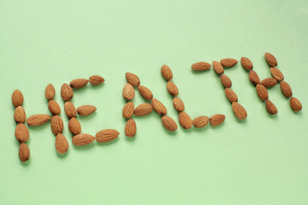 杏仁排列成绿色背景上的“健康”字样。健康饮食，生食饮食，营养，素食的理念图片下载