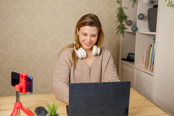 女孩坐在三脚架上的手机摄像头前录制教学视频图片下载