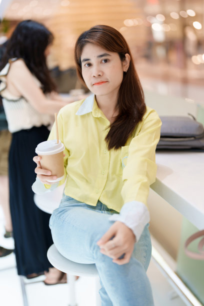 年轻女人在咖啡馆喝咖啡，手持茶杯图片下载