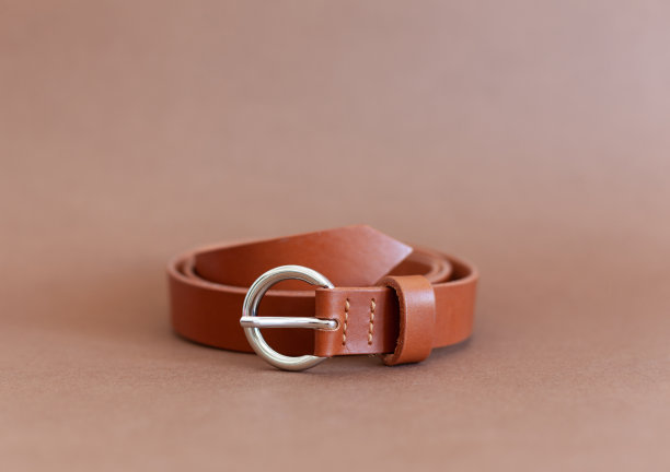 橙色妇女的皮带，由真皮，手工，躺在一个棕色的背景。图片下载