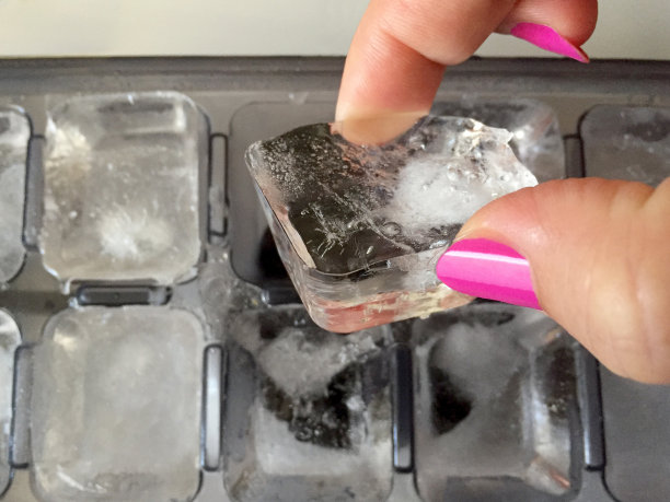 女士的手拿着冰箱里的冰块图片下载