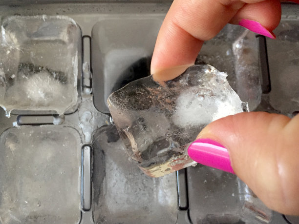 女士的手拿着冰箱里的冰块图片下载