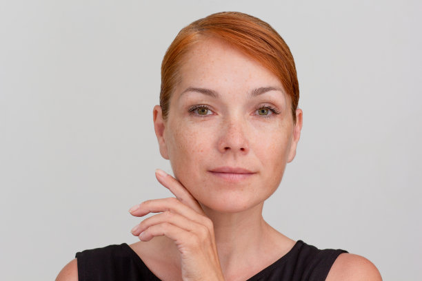 白人中年妇女的肖像，脸上有雀斑，手指在脸颊下面图片下载