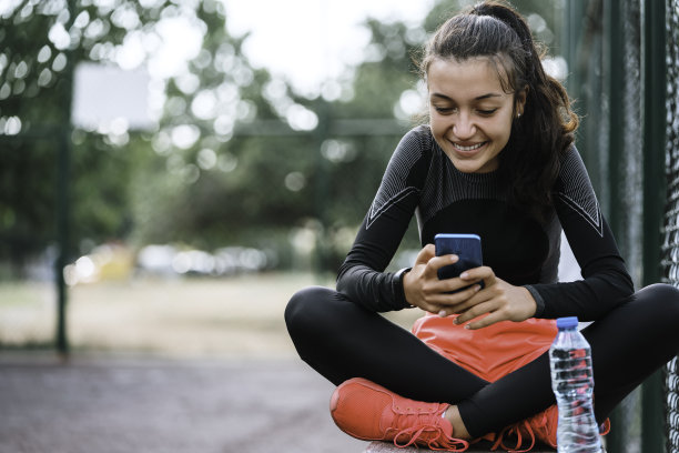 漂亮的女孩在手机上监控她的进展。图片下载