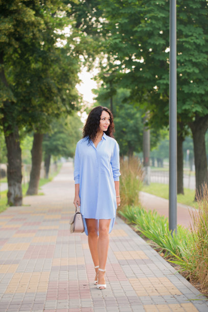一位穿着蓝色长衬衫的漂亮女商人正走在城市的小巷里图片下载