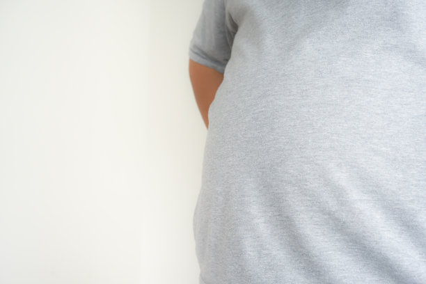 又大又胖的男人穿着普通的衣服站着展示真实的尺寸。图片下载