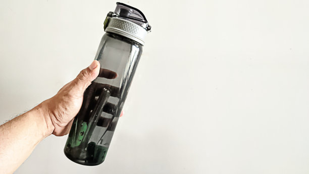 一个男人的手拿着一个透明的塑料饮料瓶图片下载