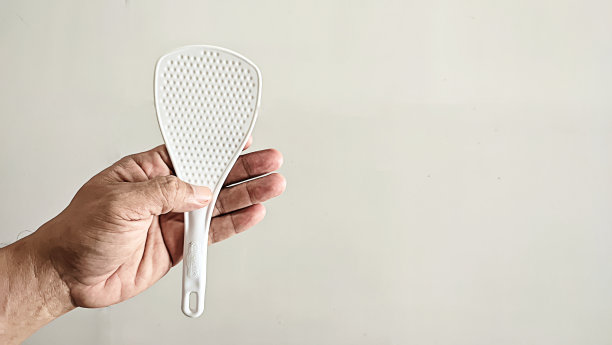 一个男人的手拿着一个塑料勺用来煮饭图片下载