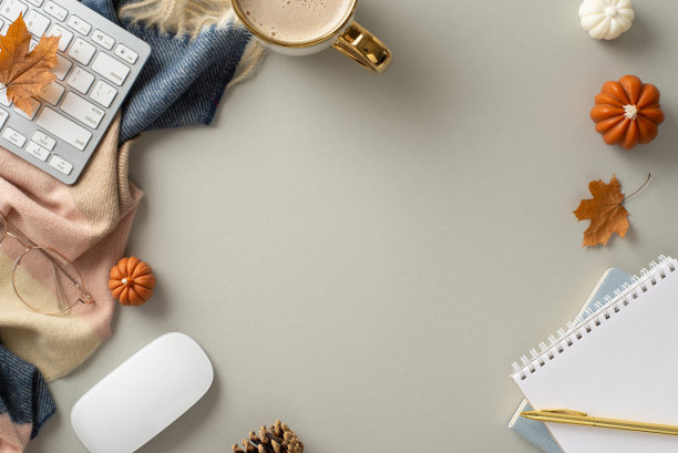 拥抱秋天的气氛在远程工作与顶视图照片具有记事本，镀金笔，眼镜，键盘，鼠标，热咖啡，斑纹围巾在一个灰色孤立的背景。适合文字或广告图片下载