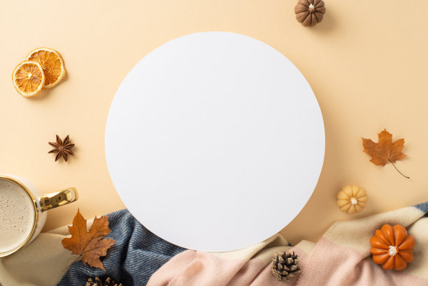 在家里享受秋天的温暖:俯视图照片展示温暖的羊绒格纹，热可可和秋天的装饰在米色孤立的背景。为圆圈内的文本或广告提供copyspace图片下载