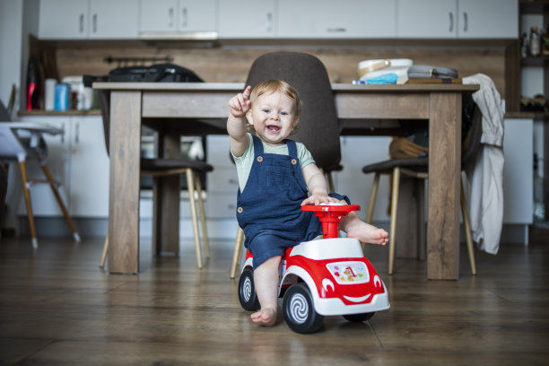 可爱的小男孩在家里玩他的玩具车。图片下载