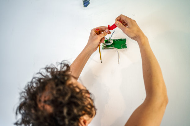 电工在装修房屋时把电源插头固定在墙上图片下载