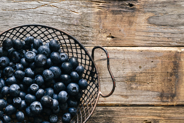 木制背景上的蓝莓金属篮子，复制空间。图片下载