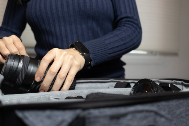 年轻女子正在整理她的相机镜头。旅行摄影师概念。图片下载